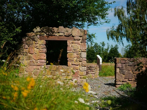 Historisches Steinportal am Geschichtspfad Dietzenbach zwischen Wiesenblumen und Bäumen