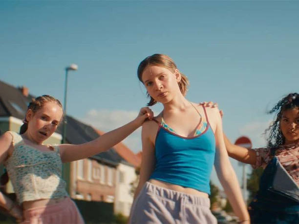 Three girls stand confidently on a sunny street; film still from *Cinepänz*.