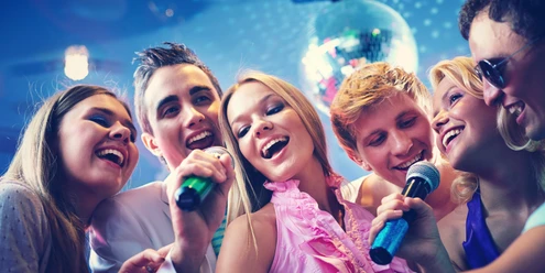 6 Freunde singen zusammen Karaoke und haben Spaß