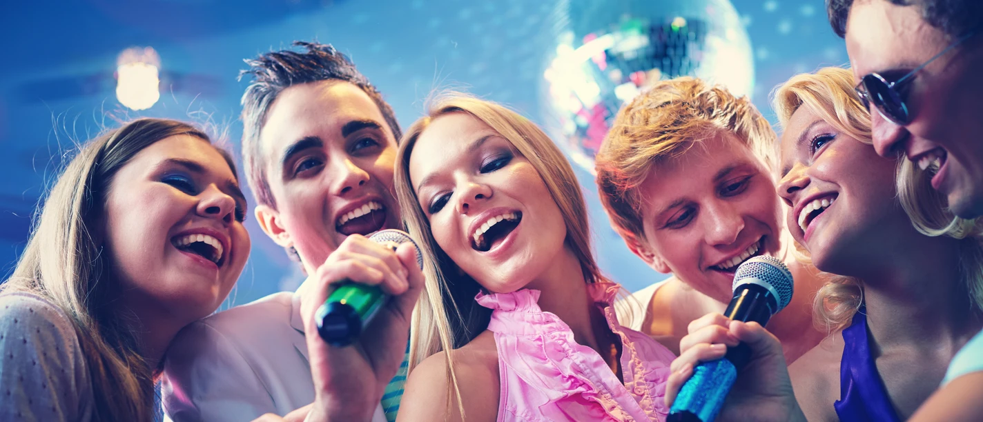 6 Freunde singen zusammen Karaoke und haben Spaß
