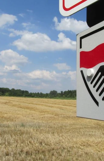 Rund um Greffen Ein Schild mit rotem Symbol steht vor einem goldenen Getreidefeld unter blauem Himmel.