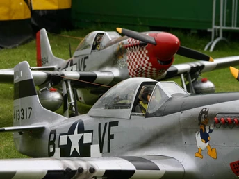 Zwei historische Flugzeuge im Vintage-Stil, lackiert in Silber mit markanten schwarzen Details.