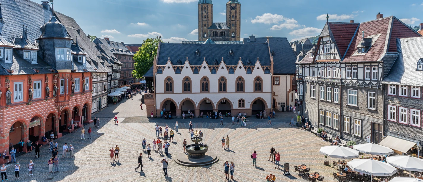 Goslars Marktplatz mit Rathaus, Brunnen, Fachwerkhäusern und Kirchtürmen.