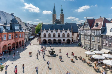 Goslars Marktplatz mit Rathaus, Brunnen, Fachwerkhäusern und Kirchtürmen.