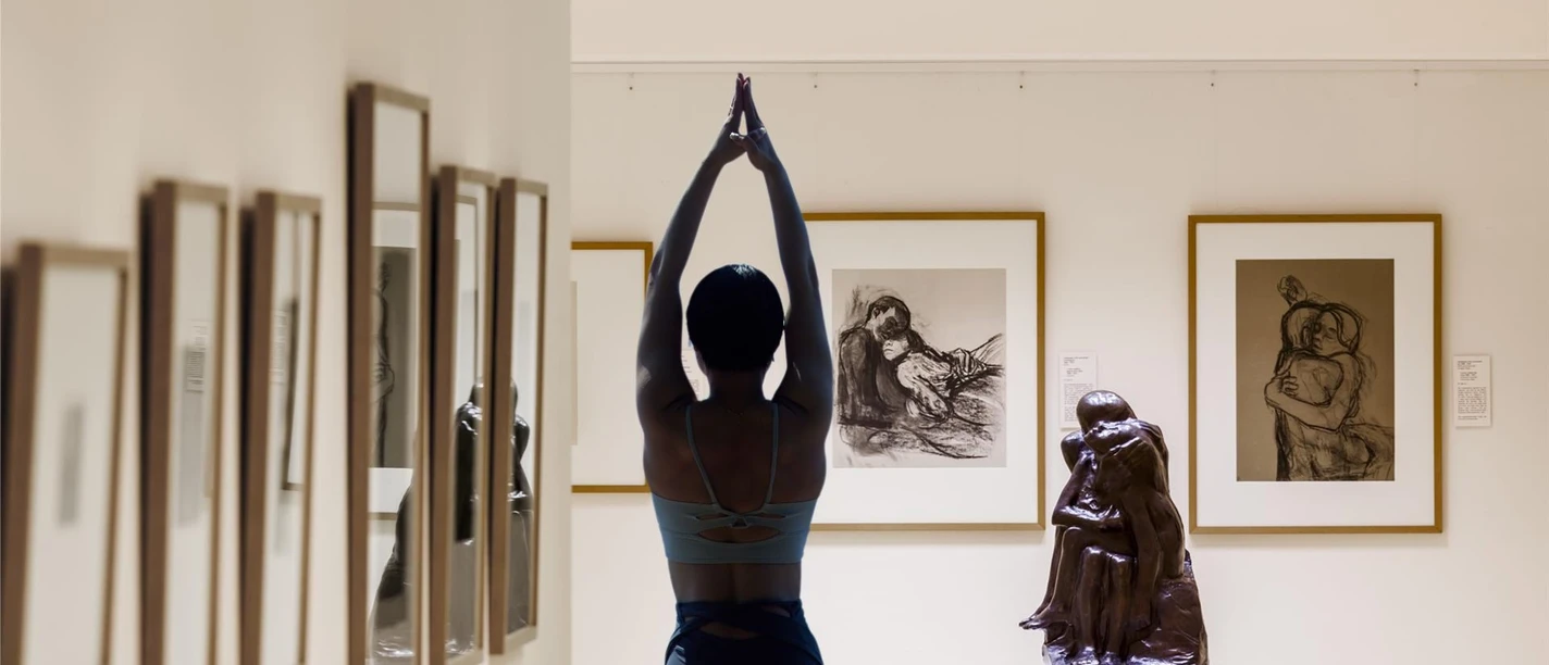 A person performing a yoga pose among drawings and sculptures at the Käthe Kollwitz Museum