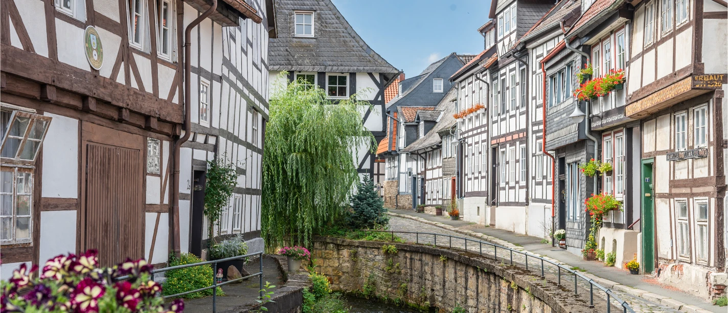 Rammebygninger ved Abzucht i Goslars gamle bydel med blomster og brosten.