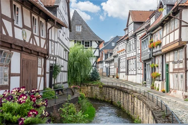 Vakwerkhuizen aan de Abzucht in de oude binnenstad van Goslar, met bloemen en kasseien.