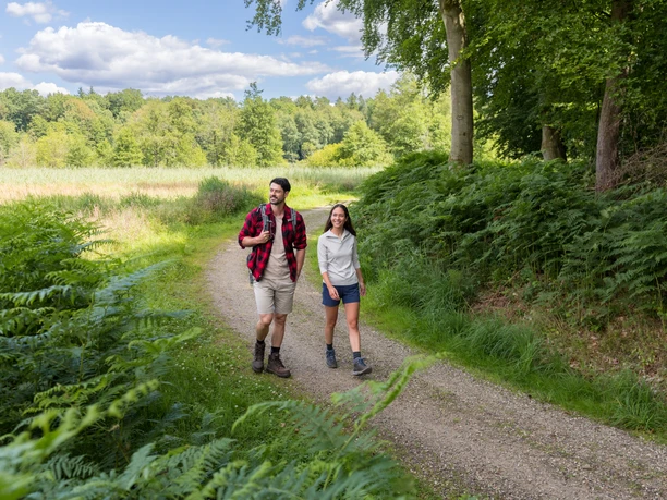 Ein Paar wandert im Hellbachtal am Waldrand.