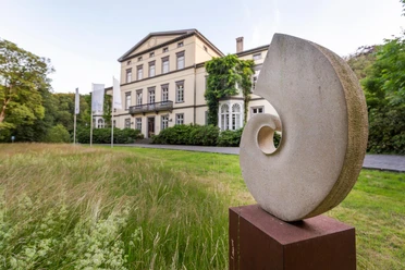 Steinskulptur Spirale von Gabriele Zutz vor historischer Villa in Engelskirchen