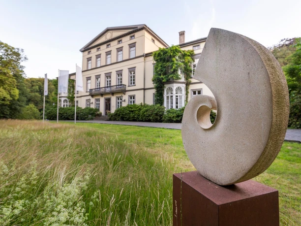 Steinskulptur Spirale von Gabriele Zutz vor historischer Villa in Engelskirchen