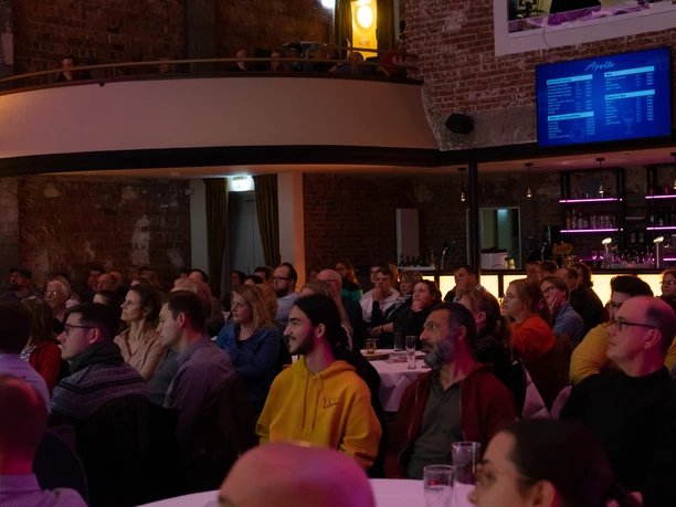 EVT01254 (c) Henry Wirth_Erlebnis Bremerhaven_WEB.jpg Publikum beim Science Slam im Apollo Bremerhaven vor Backsteinwänden und beleuchteter Bar.