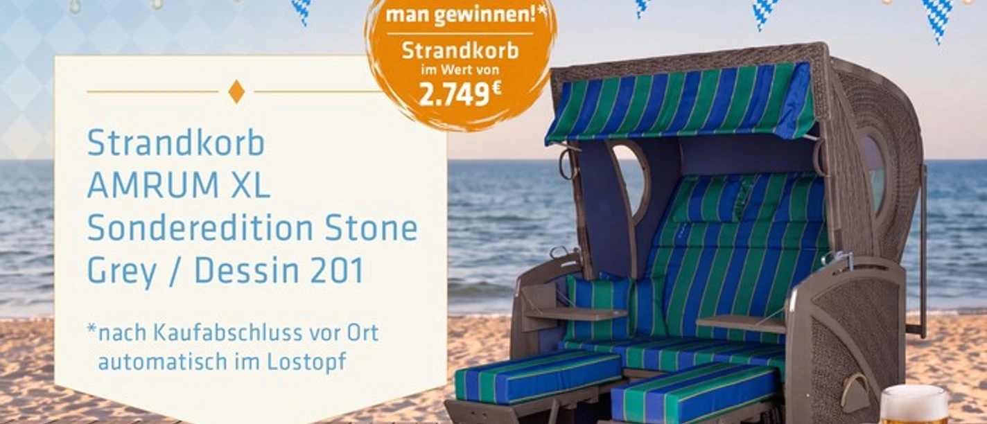 Strandkorb Amrum XL mit blau-grünen Polstern vor Strandkulisse und Oktoberfest-Deko.