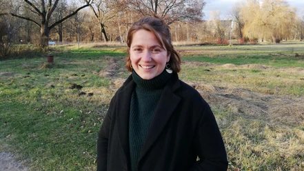 Leonie Dellen Junge Frau steht in einem Herbstlichen Park und lächelt in die Kamera