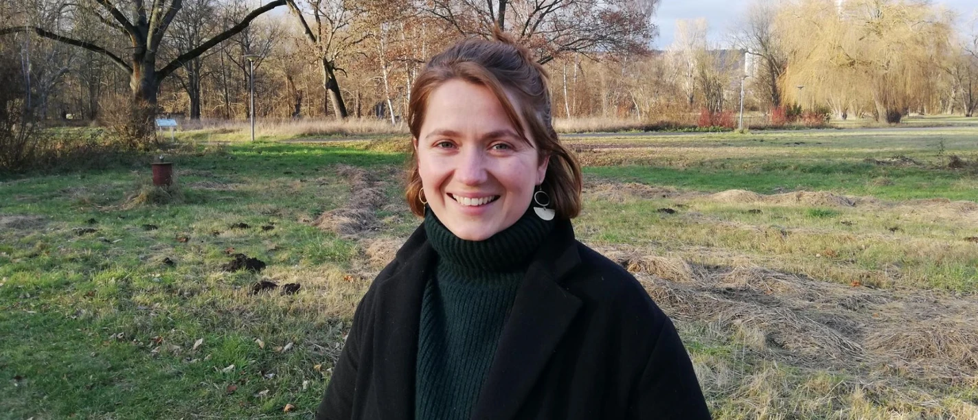 Leonie Dellen Junge Frau steht in einem Herbstlichen Park und lächelt in die Kamera