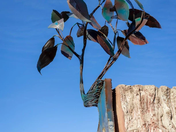 Metallskulptur Baum des Lebens mit Blättern vor blauem Himmel