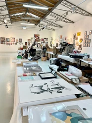 Urban art exhibition featuring prints on tables and works on white gallery walls