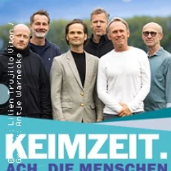Bandfoto von KEIMZEIT mit sechs Musikern vor türkisfarbenem Konzertplakat