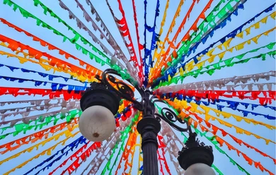 Bunte Wimpelketten über einer Laterne vor blauem Himmel beim Dorffest.