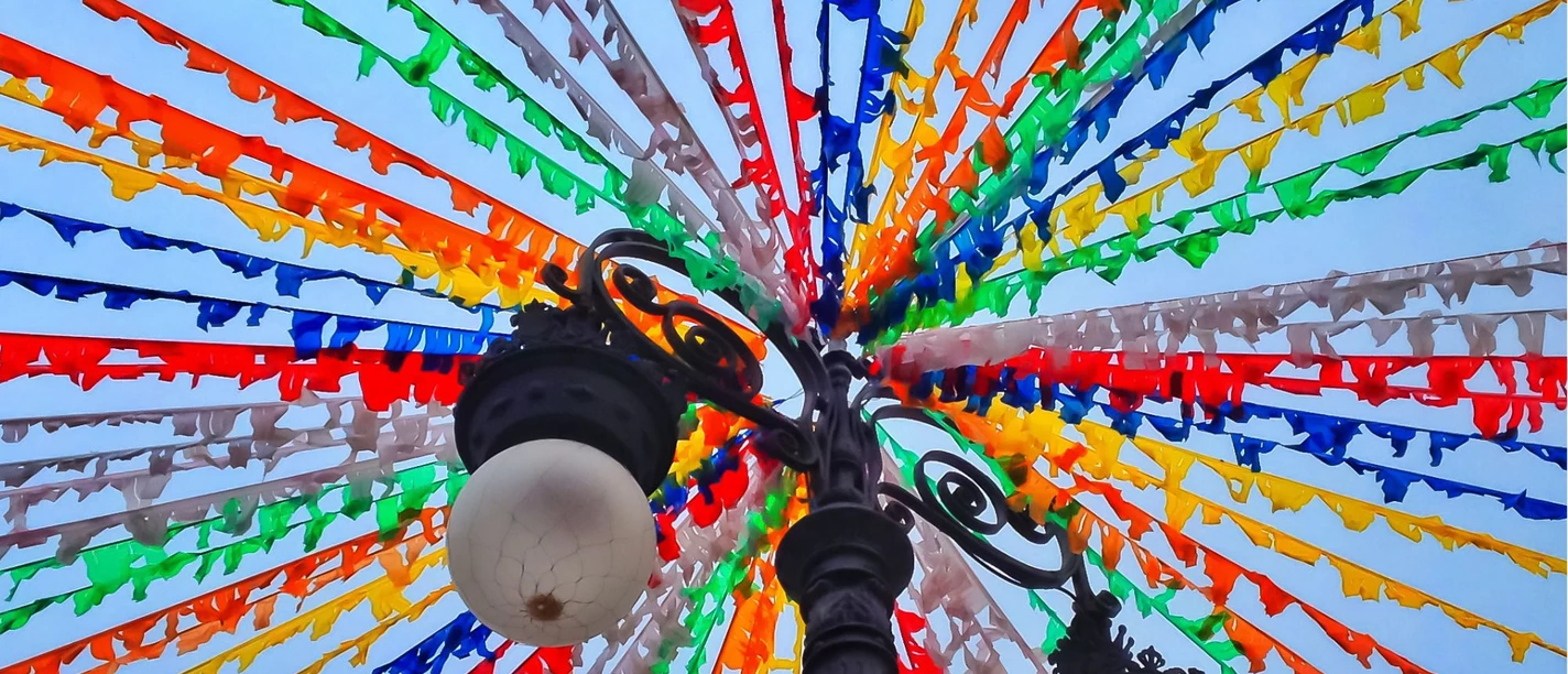 Bunte Wimpelketten über einer Laterne vor blauem Himmel beim Dorffest.