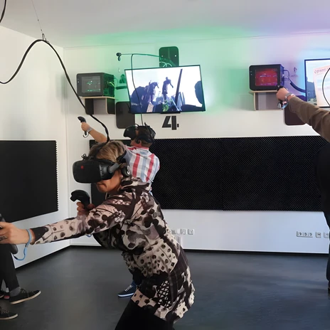 Cztery osoby w goglach VR i z kontrolerami grają razem w salonie VR Escape Leipzig.
