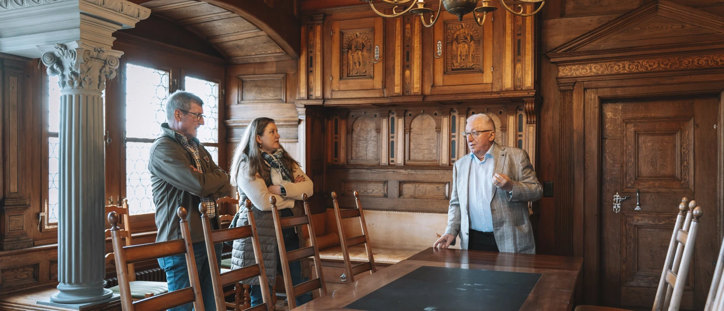 LB_Schloss-Altishofen_2026_DSC04852.jpg Führung im holzgetäfelten Rittersaal von Schloss Altishofen mit drei Personen.