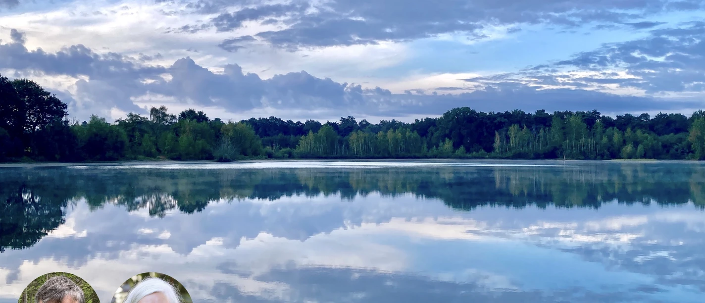 Spiegelnder See bei Dämmerung mit Bäumen und Wolkenhimmel.