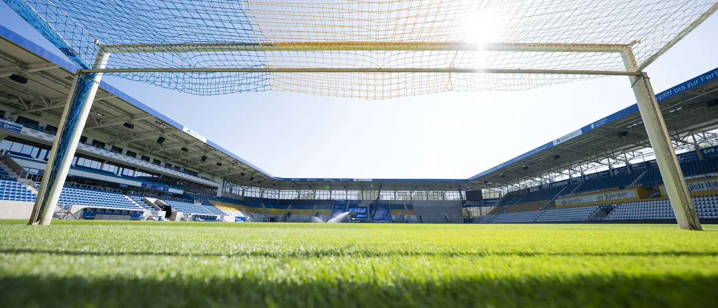 Blick vom Fußballtor auf den Platz bei Sonnenschein