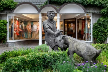 Skulptur Ziegenbrunnen mit einem Jungen und einer Ziege vor Schaufenstern in Waldbröl