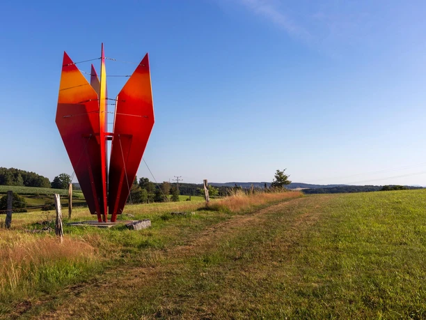 Rote Skulptur „himmelwärts“ von Wolfgang Vorländer auf einer Wiese bei Nümbrecht