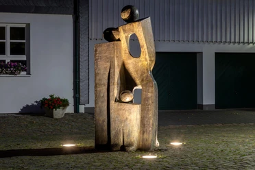 Beleuchtete, goldfarbene Skulptur „Ein Traum“ auf Kopfsteinpflaster in Nümbrecht