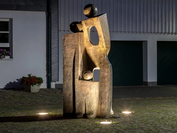 Beleuchtete, goldfarbene Skulptur „Ein Traum“ auf Kopfsteinpflaster in Nümbrecht