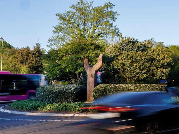 Skulptur Freundschaft im begrünten Kreisverkehr mit vorbeifahrenden Autos