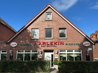 IMG_5167.JPG Backsteinfassade der Pizzeria Harlekin bei Daniel unter blauem Himmel.