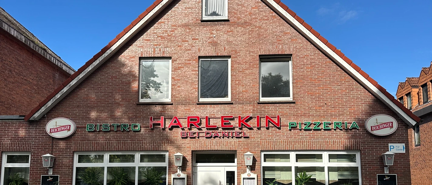 IMG_5167.JPG Backsteinfassade der Pizzeria Harlekin bei Daniel unter blauem Himmel.