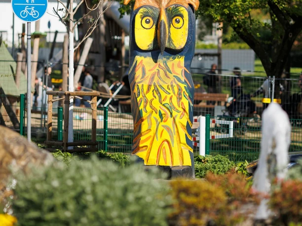 Bunte Eulenskulptur von Mike Kinne im Grünen am Eingang zum Neuen Stadtpark