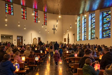 Familien mit leuchtenden Martinslaternen bei einer Andacht in der Kirche St. Augustinus in Willingen