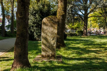 Sprechender Stein mit Inschrift zwischen Bäumen auf einer sonnigen Grünfläche in Leichlingen