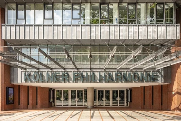 Entrance to the Cologne Philharmonic Hall with a glass canopy and signage in downtown Cologne