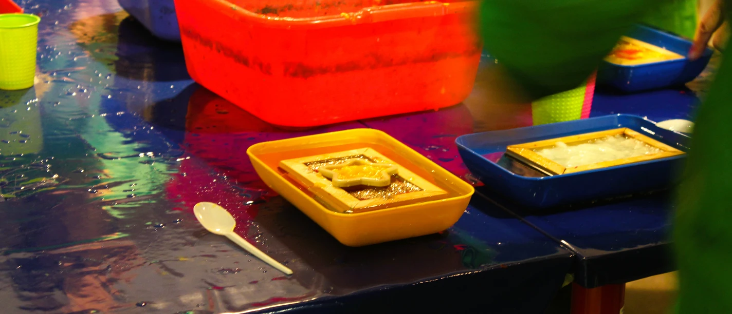 Kreatives Papierschöpfen Bunte Schalen mit Schöpfrahmen und Papiermasse beim kreativen Papierschöpfen