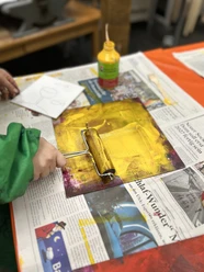 Druckwerkstatt Kinderhand rollt gelbe Farbe auf eine Druckplatte in der Werkstatt.