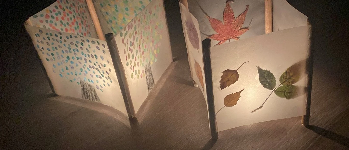 Teelichte Zwei leuchtende Papierlaternen mit Herbstblättern und bunten Punkten auf Holz