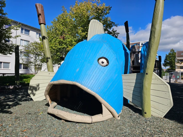 Blaues Fisch-Spielgerät mit offenem Maul auf dem Spielplatz kirchPARK.