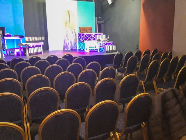 Bestuhlter Zuschauerraum mit kleiner beleuchteter Bühne im Piccolo Haventheater.