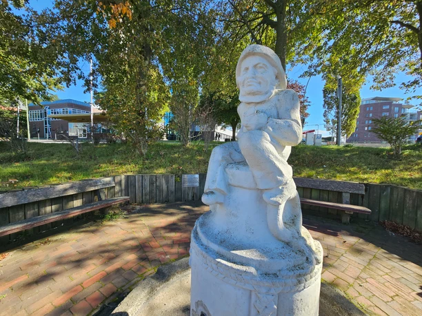 20260922_144946 (c) Tanja Mehl_Erlebnis Bremerhaven_WEB.jpg Weiße Klabautermann-Figur auf einem Brunnen, umgeben von Bänken und Bäumen.