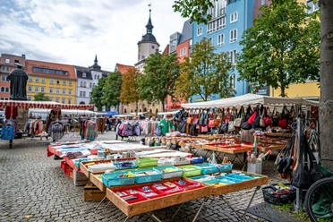 Stand auf dem Marktplatz mit Haushaltsgegenständen und Taschen