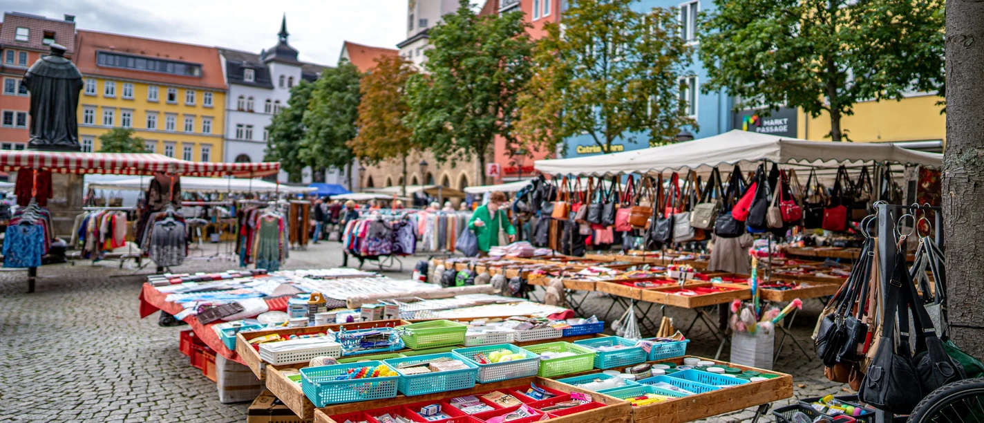 Stand auf dem Marktplatz mit Haushaltsgegenständen und Taschen