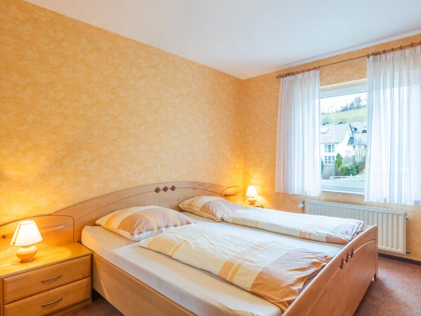 Ferienhaus zur Schlade, Schlafzimmer Schlafzimmer mit Doppelbett, Nachttischen, warmem Licht und Fensterblick