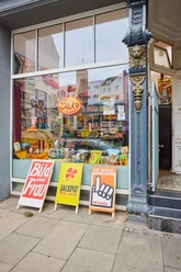 A colorful display window for the "Silky Späti" exhibition featuring Pop Art signs in Cologne
