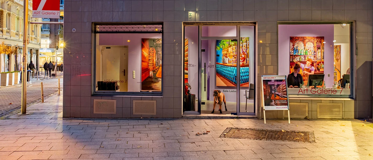 Abendliche Außenansicht der Art Galerie 7 in Köln mit beleuchteten Schaufenstern.
