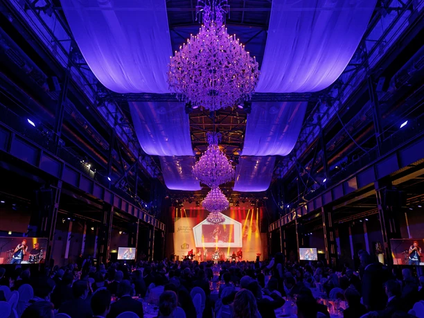 A gala evening with a stage, an audience, chandeliers, and violet-blue lighting effects